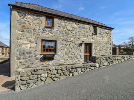 A stone wall with a door and windows at Bluebell Cottage Caeathro near Caernarfon