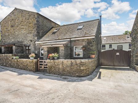 A stone cottage with flower pots on the wall and a wooden gate at Thimble Cottage in Pennington near Ulverston