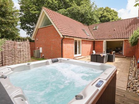 An outdoor patio area with a hot tub dining table and chairs at Oak Tree Lodge in Crostwick near Norwich