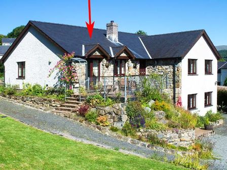 A house with stone and white walls a slate roof and a garden path with plants at Llety'r Bugail in Dolgellau
