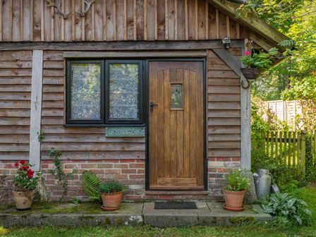 A wooden door with a window and flower pots outside a wooden cabin at Endymion Linwood near Ringwood New Forest
