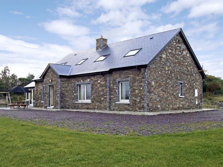 A stone house with skylights and a picnic table with umbrella in the yard at River House in Sneem County Kerry