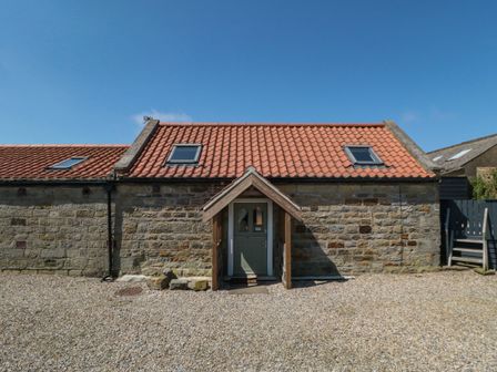 An exterior view of a stone building with a red tiled roof and a wooden porch at Barn Cottage High Normanby near Robin Hood's Bay