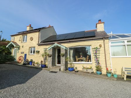A house with solar panels and potted plants at Crow's Nest Cottage in Tynygongl near Benllech