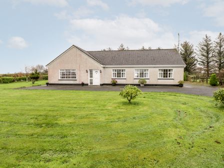 A one-story house with a tiled roof and multiple windows on a lawn with small bushes at Dromore West Cottage in Dromore West County Sligo