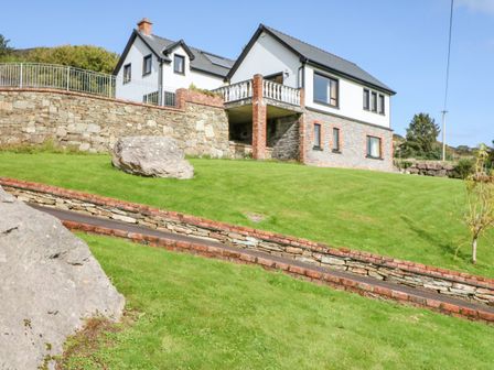 A house on a grassy hill with stone retaining walls and large rocks at Ocean View in Adrigole County Cork