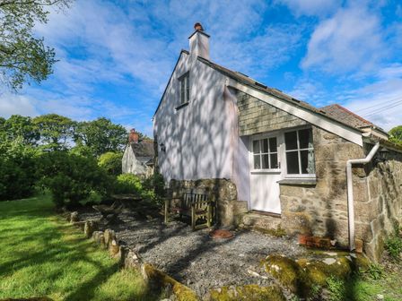 A house with a bench and table surrounded by grass at Longhouse in St Keverne, Lizard Peninsula