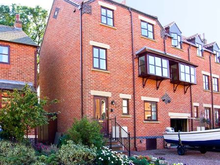A brick townhouse with a garden and a boat on a trailer at Waters Edge in Ruswarp near Whitby