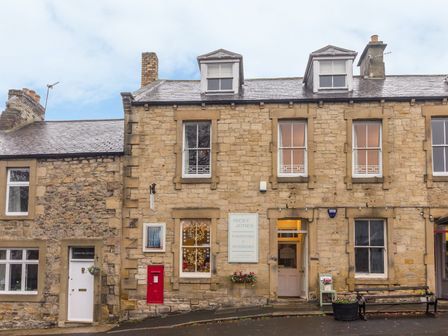 Stone building with multiple windows and a red mailbox on a street at The Old Exchange in Corbridge near Hexham
