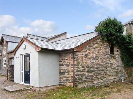 An exterior view of a stone and plaster building with a black door and a small ramp at Hendre Aled Cottage 1 in Llansannan near Llanrwst