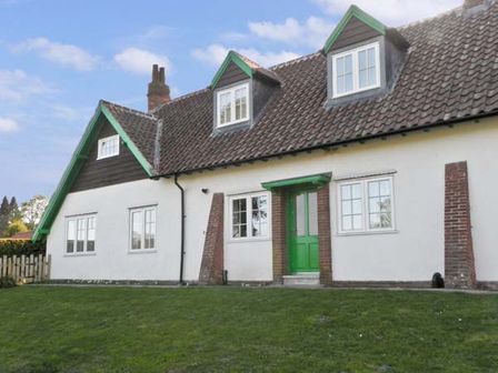 A white cottage with green trim and roof windows on a grassy lawn at No 2 Low Hall Cottages Scalby near Scarborough