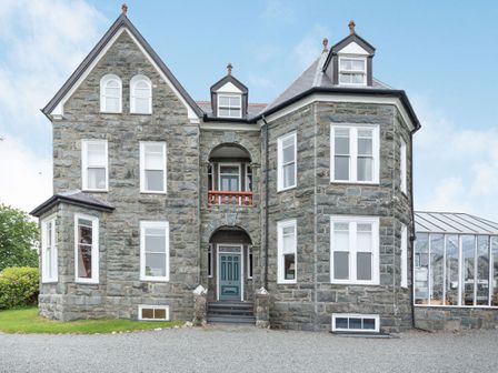 A stone house with multiple windows and a glass extension at Pensarn Hall in Llanbedr near Harlech