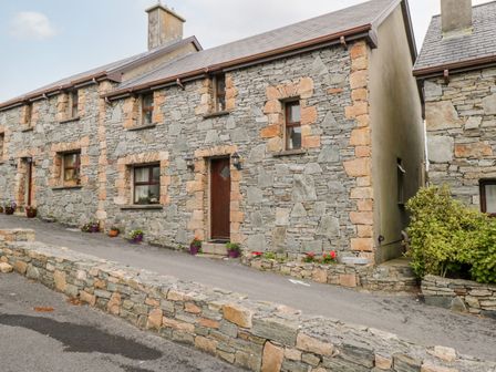 A stone cottage with flower pots along the front at King Cottage in Cleggan near Clifden County Galway