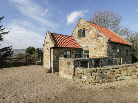 A stone cottage with red tile roof and stone wall in front at The Piggery in Sleights near Whitby