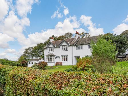 A white two story house with a hedge and garden in front at Peel Place Noddle Eskdale Green