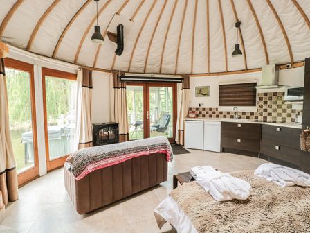 A circular living space with a sofa table kitchenette and bed at Island Yurt in Beckford near Tewkesbury