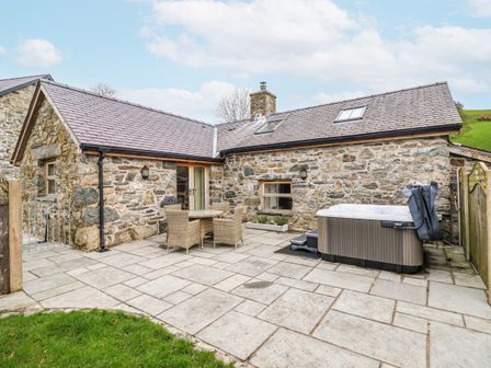 An outdoor seating area with a hot tub and dining furniture at Briws and 963354 together they sleep 35