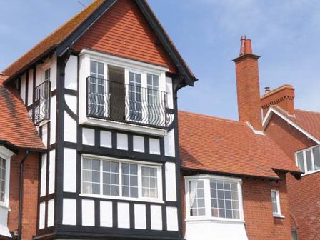 Exterior of a house with black and white timber framing red roof and multiple windows with balcony Sandy Shore Bridlington
