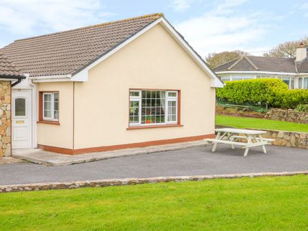 The exterior of a one story house with a white door a large window and a picnic table on a paved area at Island View in Ardmore County Waterford