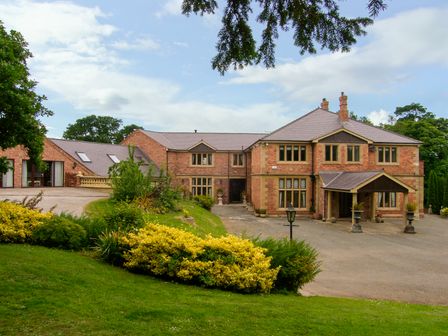 A large brick house with multiple windows and a garden in front at Richmond Hall in St Asaph