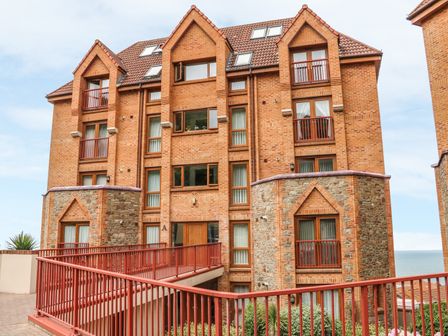 A multi-story brick apartment building with balconies and stone accents by the sea at 37 Ocean Park in Westward Ho