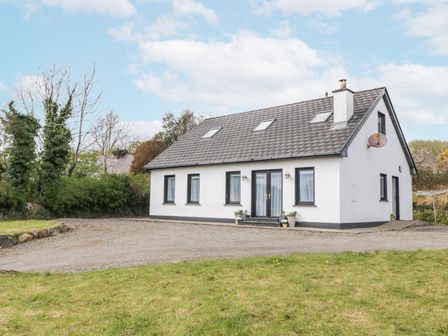 A detached house with white walls and a grey roof surrounded by grass and trees at Loistin Coimin Commeen near Ballybofey County Donegal