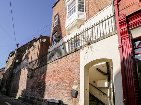 A brick building with an arched entrance and stairs on Newton Street at Nutshell in Whitby