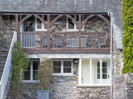 A stone house with a wooden balcony and stairs outside at Lords Leap in Graythwaite near Hawkshead