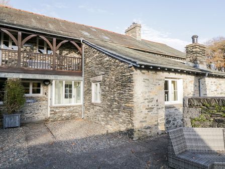 Stone house exterior with wooden balcony and gravel pathway at Bassicks in Hawkshead