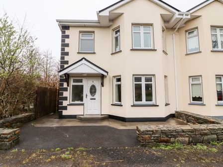 Exterior of a cream two-story house with white framed windows and a white front door numbered 4 with stone walls on both sides at Culann in Clifden County Galway