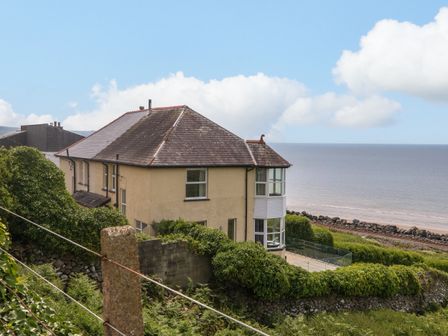 A house with a slanted roof near the sea with railway tracks in the background at Morolwg in Llanaber near Barmouth