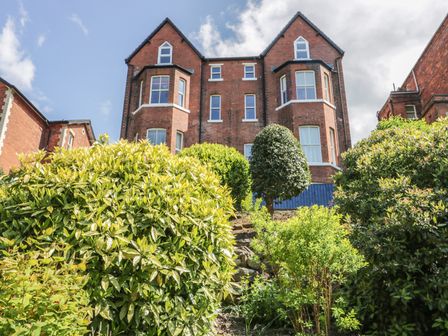 A brick residential building with multiple windows and bushes in the foreground at Carisbrooke in Scarborough