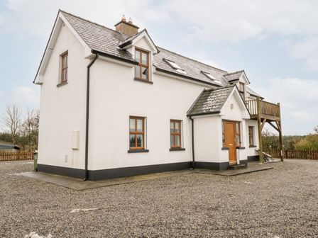 A two-story house with multiple windows and a small balcony over a gravel driveway at Errit in Loughglynn near Ballaghaderreen County Roscommon