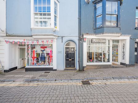 A street view with British Red Cross shop and Audrey Bull Antiques shop with a black door in between at Berlin House in Tenby