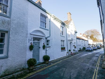 A narrow street with white buildings and parked cars at Cartmel Flat in Cartmel