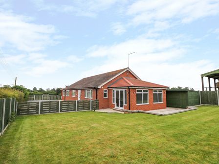 A brick house with a lawn and wooden fences at Pinfold View in Seaton near Hornsea