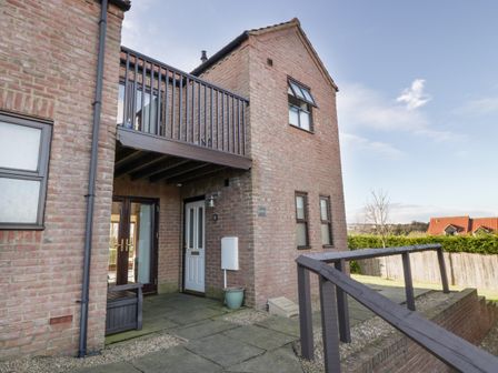 An exterior view of a brick house with a balcony and a white front door at Buffers in Whitby