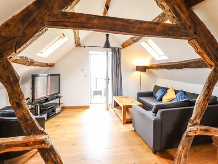A living room with wooden beams sofas coffee table and television at Ysgubor Las in Dolgellau