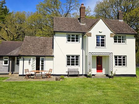 A white two-story house with a red door and outdoor furniture on a lawn at Chasewoods Farm Cottage Ogbourne St George near Marlborough