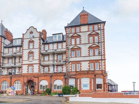 The exterior of a multi-story building with red brick and white walls featuring multiple windows and balconies at Cairns Vista in Whitby