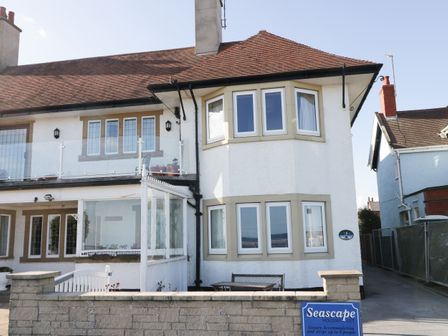 A two story house with white walls and brown roof with a sign Seascape holiday let in Bridlington