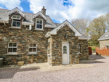 The exterior of a stone cottage with white framed windows and a white door at Lis-Ardagh Cottage 1 in Union Hall County Cork