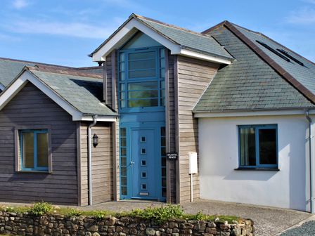 The exterior of a modern house with blue framed windows and door at Atlantic Reach in Widemouth Bay