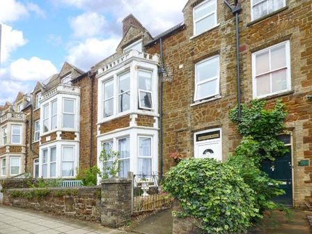 A row of stone terraced houses with bay windows and green plants in front at Westgate Retreat in Hunstanton