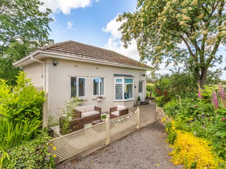 Outside view of a single story house with patio furniture and surrounding garden at Bracken Barn Cottage in Widdrington near Amble