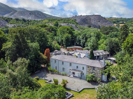 An aerial view of a large house surrounded by trees and hills at Bryn Derwen Bethesda near Caernarfon