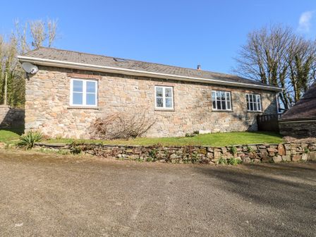 A stone exterior building with four windows and a gravel driveway at Llety'r Llwynog in Llanfallteg near Narberth