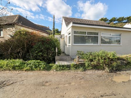 A single story house with large windows and bushes in front at Driftwood in Polzeath near Wadebridge