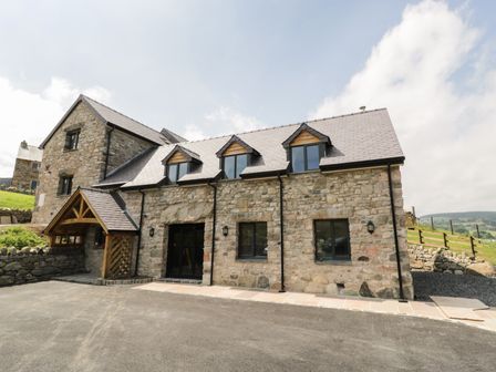A stone building with a slate roof and multiple windows in a rural area at Tyn Y Celyn Isaf in Clocaenog near Ruthin