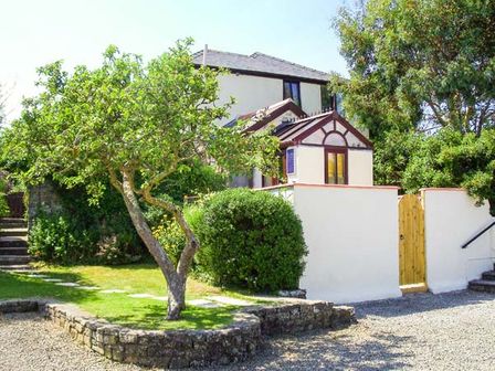 A house with a garden tree and a stone wall with a wooden gate at Groom Cottage in Poughill near Bude
